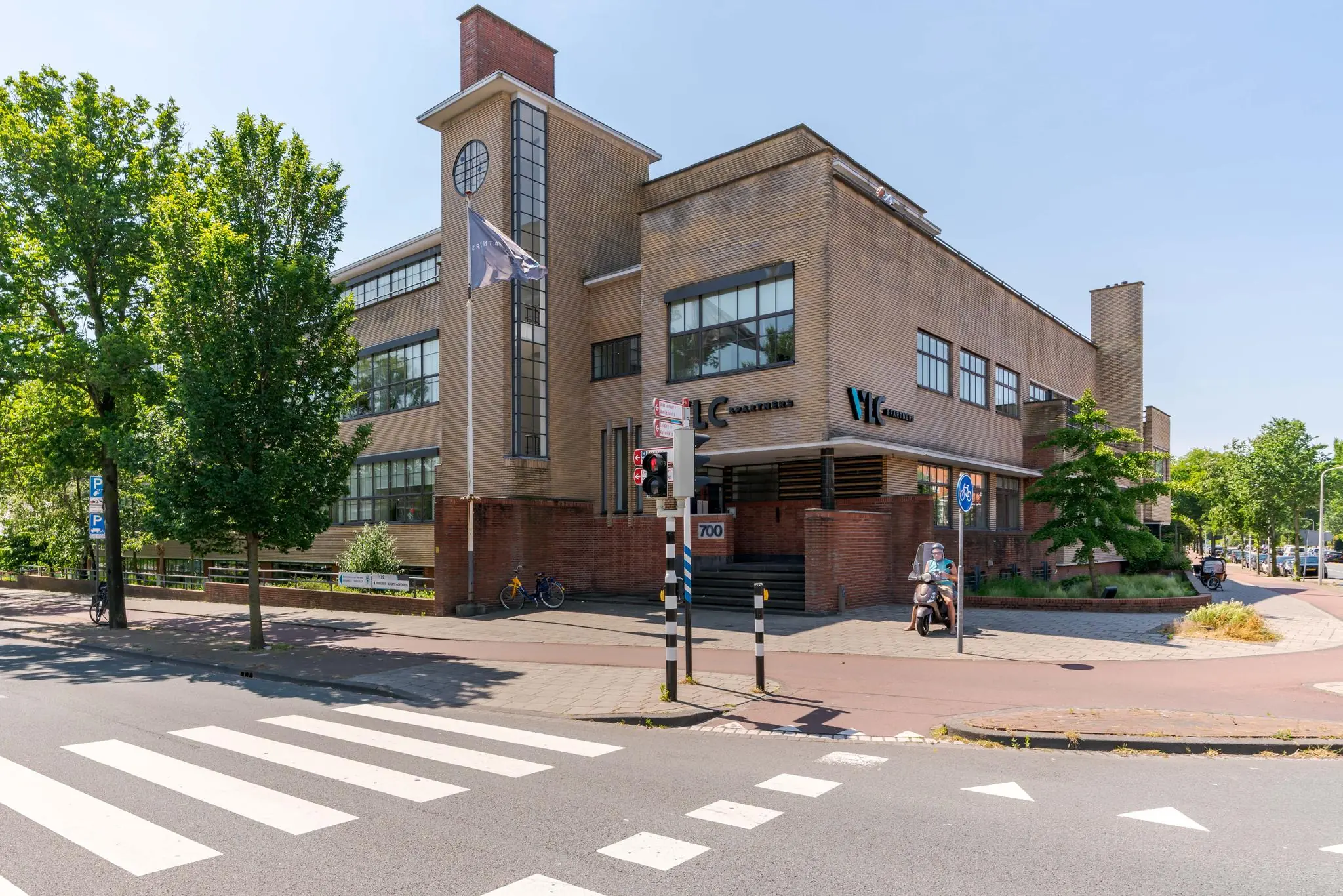 Vooraanzicht van het markante kantoorgebouw aan de Van Alkemadelaan 700 in Den Haag op een zonnige dag.